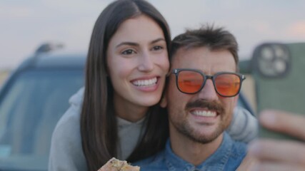 Canvas Print - Modern couple enjoying a road trip with their car, taking a selfies and eating a fast food