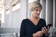 © TasJam/peopleimages.com - Mature, woman and cellphone in city for business, networking and app for directions. Technology, corporate female person and online in street for connectivity, communication and travel for career