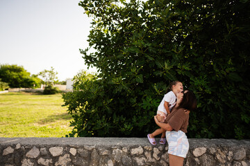 Sticker - Mother lifting daughter in playful moment outside on a sunny day