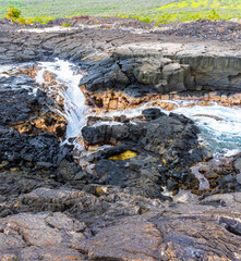 Wall Mural - Water Rushing Over The Lava Sinks and Cliffs at Hokulia Shoreline Park, Hawaii Island, Hawaii, USA