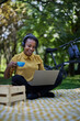 © kerkezz - a beautiful smiling young woman sitting in the park and working on a laptop