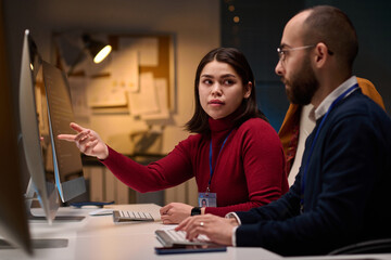 Portrait of computer development team discussing project in office with young woman pointing at screen