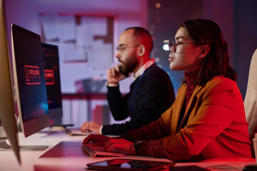 Side view portrait of computer programmers working in cybersecurity department with red emergency lights copy space