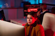 © Mediaphotos - Portrait of young woman using computer in cybersecurity department lit by red neon light copy space
