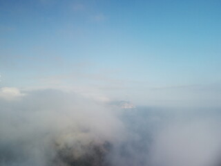 Wall Mural - aerial view. blue sky sun and fog over calm sea. the drone flies over foggy and fluffy clouds. abstr