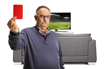 Wall Mural - Serious mature man showing a red card in front of a tv screen