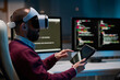 © Mediaphotos - Side view portrait of bearded man wearing VR headset and using tablet working on mixed reality project in blue lights copy space