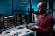 © Mediaphotos - Side view portrait of bearded adult man as computer programmer holding open laptop in IT and cybersecurity office with blue lights copy space