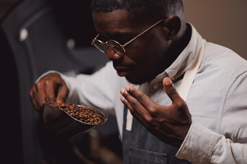 African american man barista testing aroma of fresh coffee beans after roasting machine industry, small business cafe