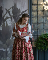 Wall Mural - An aristocratic girl in a vintage dress reads a book