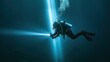 © MakoPoko - Scuba diver descending into the depths with a powerful underwater flashlight, creating a beam of light.