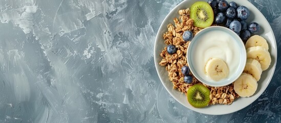 Wall Mural - Top view of delicious granola topped with blueberries kiwi and banana on a grey table designed as a banner with copy space image