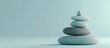 © Ilgun - Zen pebbles are carefully balanced on a light blue background in a peaceful studio photography setting creating a soothing atmosphere for relaxation and meditation with copy space image included