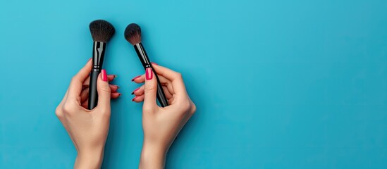 Poster - A blue background with female hands holding makeup brushes creating a vibrant copy space image