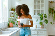 © Hanna - Young Woman in Bright Kitchen Checking Phone While Smiling in Late Morning
