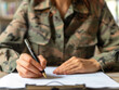 © alfa27 - A woman in a military uniform is writing with a pen on a piece of paper