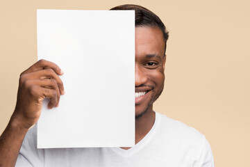 Canvas Print - Smiling African American Man Holding Blank Paper Sheet Covering Half Of His Face Standing Over Yellow Background. Mockup