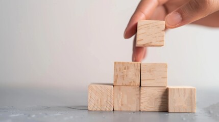 Hand Stacking Wooden Blocks to Build a Tower Representing Growth and Development