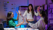 © amnaj - Three young asian businesswomen giving high five to celebrate the success of a new project in a modern office at night