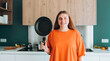 © mdyn - Young woman housewife holding empty pan in the kitchen at home. Domestic life and diet concept. Food banner. Time to eat
