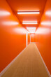 © ADDICTIVE STOCK - Long corridor with vibrant orange walls and ceiling lights