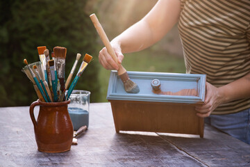 Painting a wooden furniture outdoors, an eco-friendly re-use business.