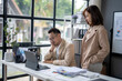 © Wasana - A man and a woman are sitting at a desk with a laptop