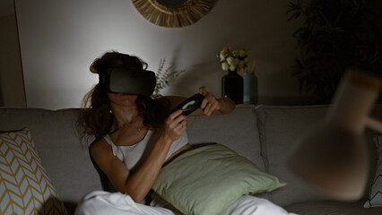 Sticker - A young woman enjoys virtual reality gaming at home on a cozy couch, immersed in modern technology.