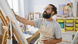 © Krakenimages.com - Bearded man painting in a bright art studio, showcasing creativity and concentration.