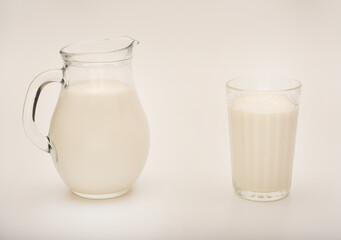 Melted milk in a milk jug and in a glass on a white background. Milk in a bowl.