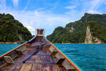 Wall Mural - View from the  boat bow to rock islands on Cheo Lan lake at Surat Thani province of Thailand. Picturesque landscape of national Khao Sok park, scenic background for summer travel