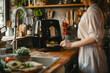 © artesenc - A person in a kitchen using an air fryer with various foods