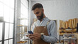 © Krakenimages.com - Young hispanic man with beard using cellphone in bakery shop interior with shelves of bread in the background