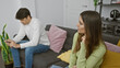 © Krakenimages.com - A pensive woman and man sit separated on a sofa in a modern living room, reflecting a tense couple dynamic.