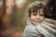 © ChaoticMind - A joyful young boy with curly hair smiles while embracing an adult in an outdoor setting, with soft light and a forest background enhancing the moment.