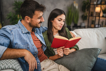 Wall Mural - relax couple boyfriend and girlfriend sit on sofa and read a book