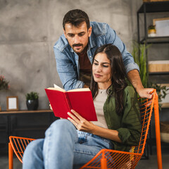 Wall Mural - Girlfriend sit and read a book whit boyfriend stand next to her