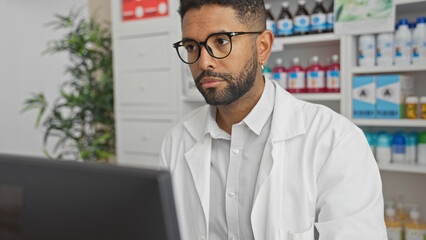 Wall Mural - A focused african american male pharmacist in glasses working indoors at a drugstore counter.