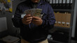 © Krakenimages.com - Close-up of a young hispanic man holding american dollars in a police station office.