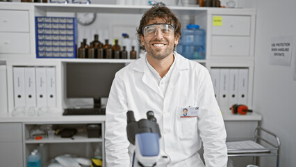 Wall Mural - Smiling man with beard and safety glasses in white lab coat inside chemistry laboratory