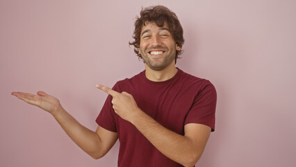 Sticker - Handsome young hispanic man with a beard presenting or showing something, isolated against a pink wall background.