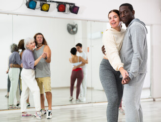 Wall Mural - African man and caucasian young woman learning paired latin dances