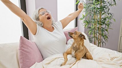 Sticker - Mature woman stretching with her dog in a cozy bedroom, evoking a relaxed morning routine