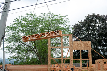 Wall Mural - Residential house construction, boom crane lifting lumber delivery, wood support truss beams, to next floor of in project
