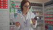 © Krakenimages.com - A professional woman pharmacist examines medicine while holding a prescription in a well-stocked pharmacy.