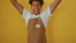 © Krakenimages.com - Young man in a brown apron exuberantly celebrating over an isolated yellow background.