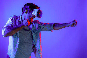 Side view of man wearing VR glass and smashing or punching at camera. Professional sport gamer boxing and moving gesture in metaverse or virtual world while using technology innovation. Deviation.