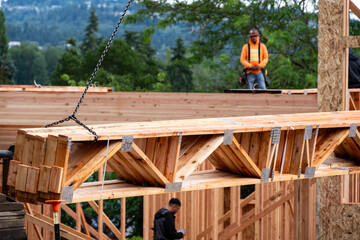 Wall Mural - Residential house construction, boom crane lifting lumber delivery, closeup of wood support truss beams being lifted, workers in background
