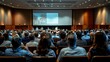 © NoorZafirah - Photo of a Diverse Group Seated and Engaged in a Conference Hall, Large Screen Display, Rear View