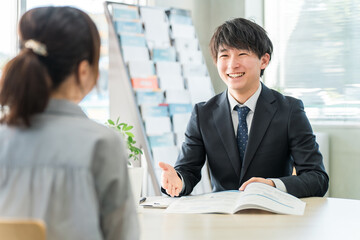 Canvas Print - パンフレット・カタログを使い女性客と商談する若いアジア人ビジネスマン（自動車・保険）
